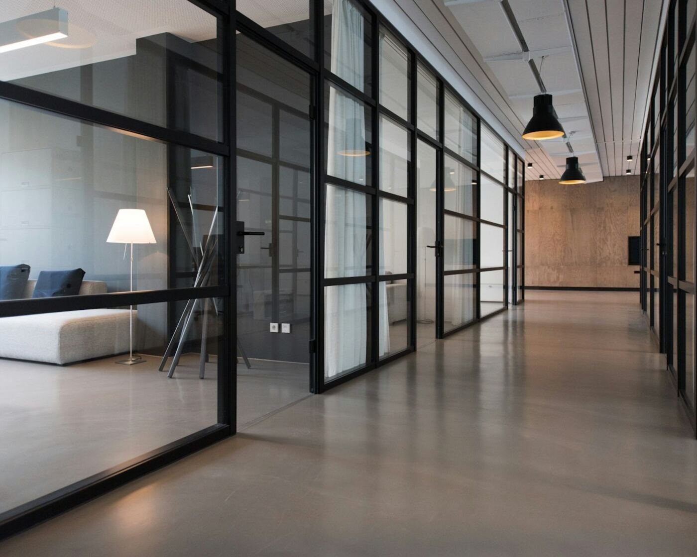 Empty modern office hallway with glass-walled meeting rooms
